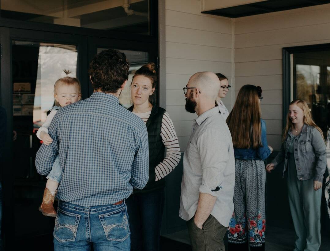Adults and children mingle outside of Emmaus Road Church in Bozeman, MT as they visit on Sunday morning